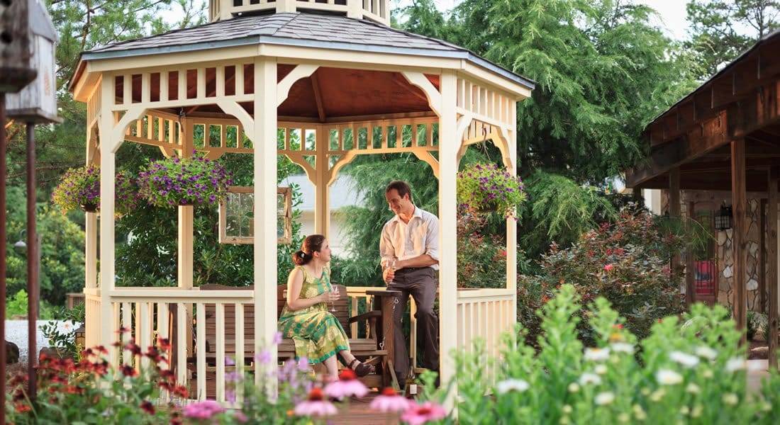 A couple sitting in the gazebo with flowers and greenery all around