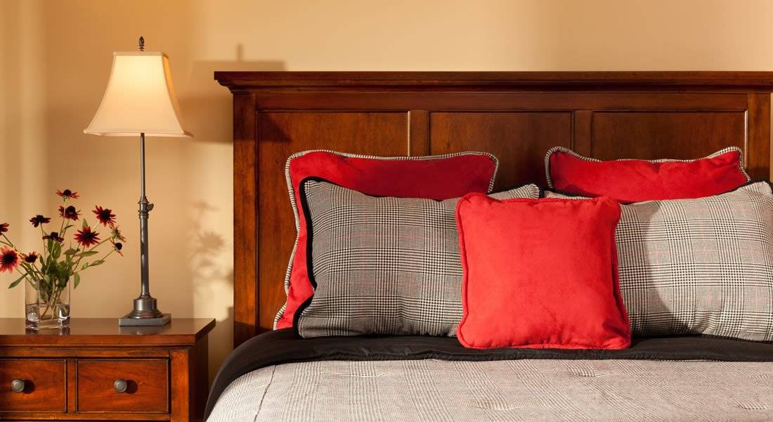 Wood headboard with burgundy pillows and stripped black and white