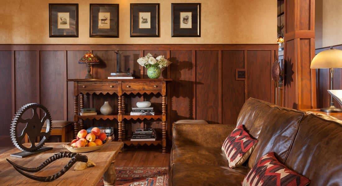 Sitting area with Leather couch  coffee table with apples, wood panels half way up the wall