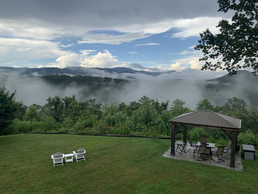 A grassy area overlooking the rolling Blue Ridge mountains that are covered with patches of misty fog.