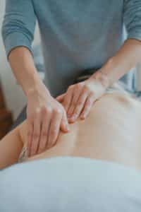 A massage therapist uses both hands to massage a person's back.