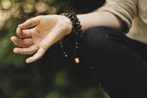 A arm with a beaded bracelet in a meditative position.