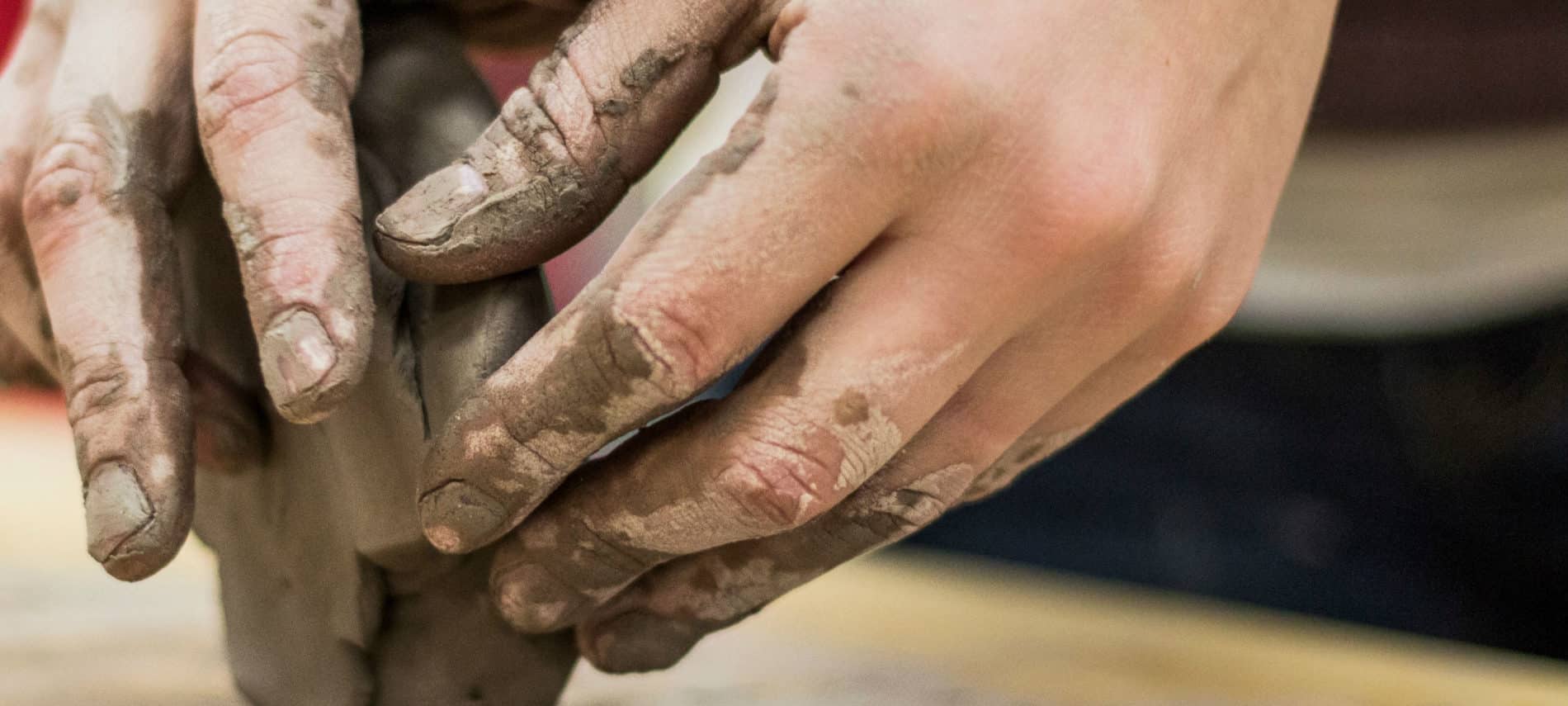 A closeup  of a potter hands working with clay. Title Pottery on display in Clarkesville, GA