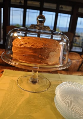 Glass cake dish with a chocolate icing cake in the living room