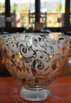 a glass bowl with a design on it, sitting on the table in the dinning room. 
