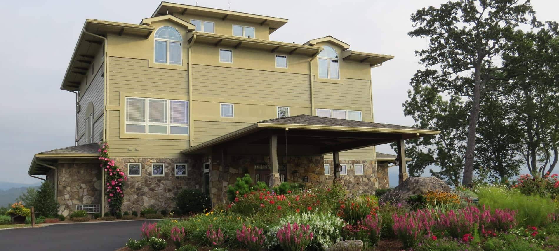 Front of the Inn with light green siding with the wild gardens in the fore ground