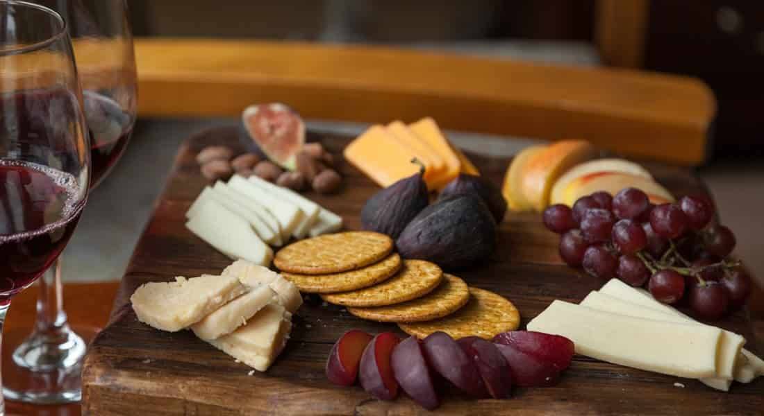 Cheese, crackers, grapes set up on a cutting board