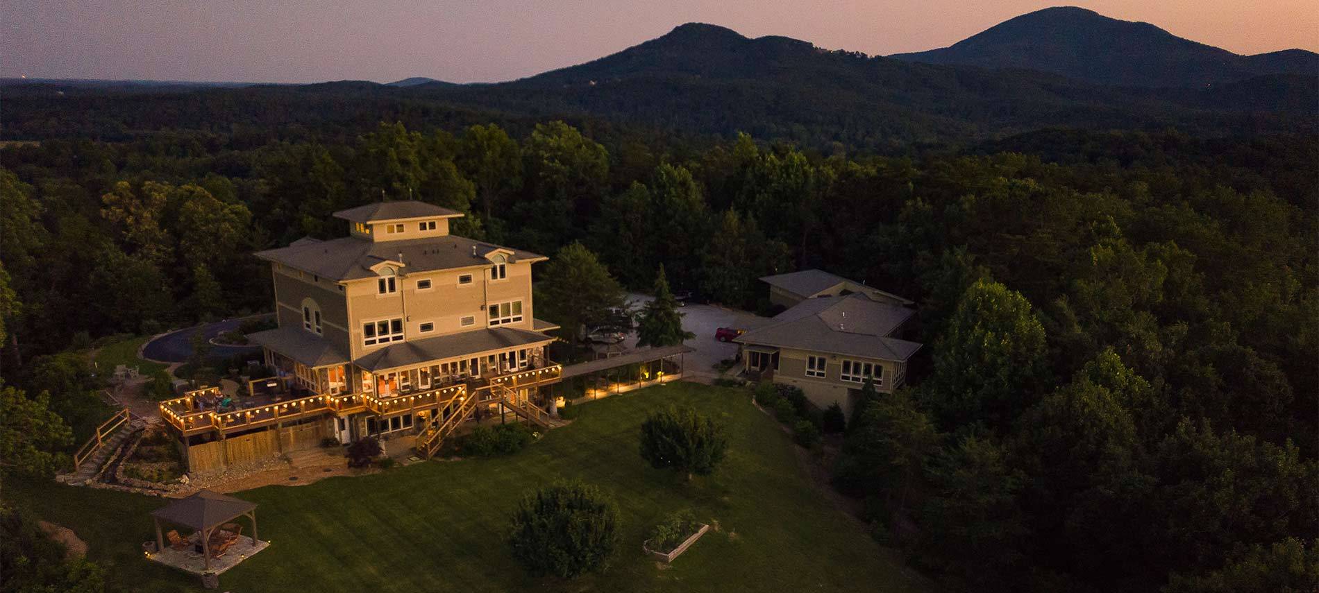 Arial shot of the Inn with the Mountains in the background and the sun is setting on the Inn.