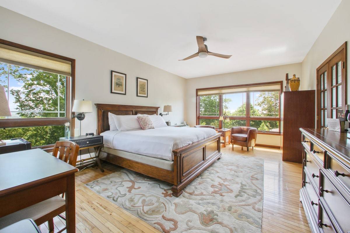King bed with a light green bedspread with a medium wood Head and footboard. Large windows with a view of the Mountains 