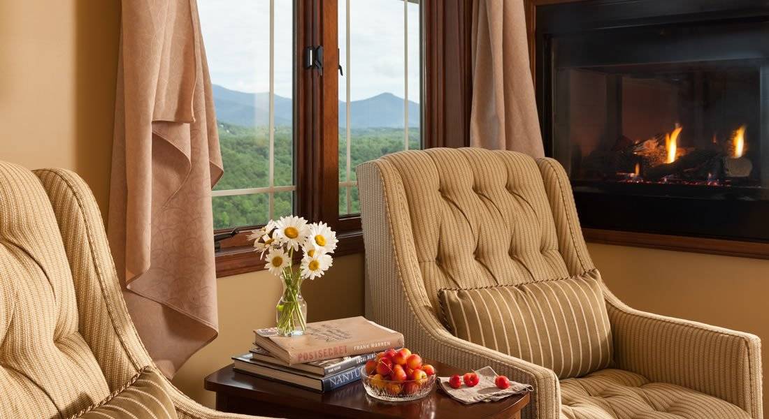 Lite tan chair in the sitting area with a see thru gas fireplace and a window with a view of the mountains
